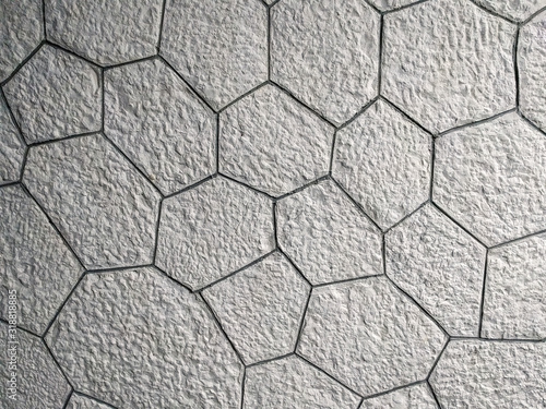 Interesting pattern of hexagonal shaped white bricks on the wall or floor, made of rock stone and a modern wallpaper background
