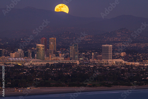 A full moon rises over the mountains and skyline of downtown San Diego, California. Nice reflection on the water. photo