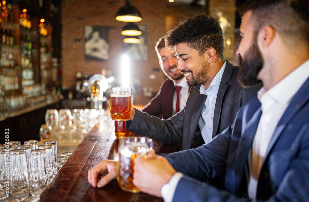 People, friendship and celebration concept. Happy business male friends drinking beer at pub