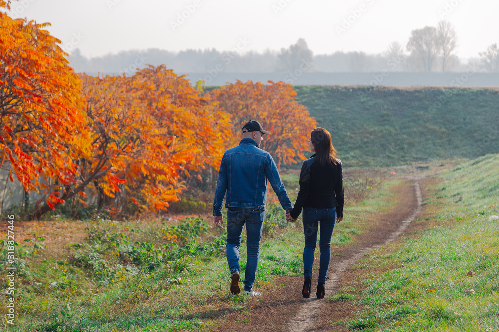 Loving couple walks in the autumn along the alley.