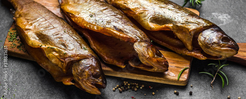 Photography Smoked fish with spices on dark background