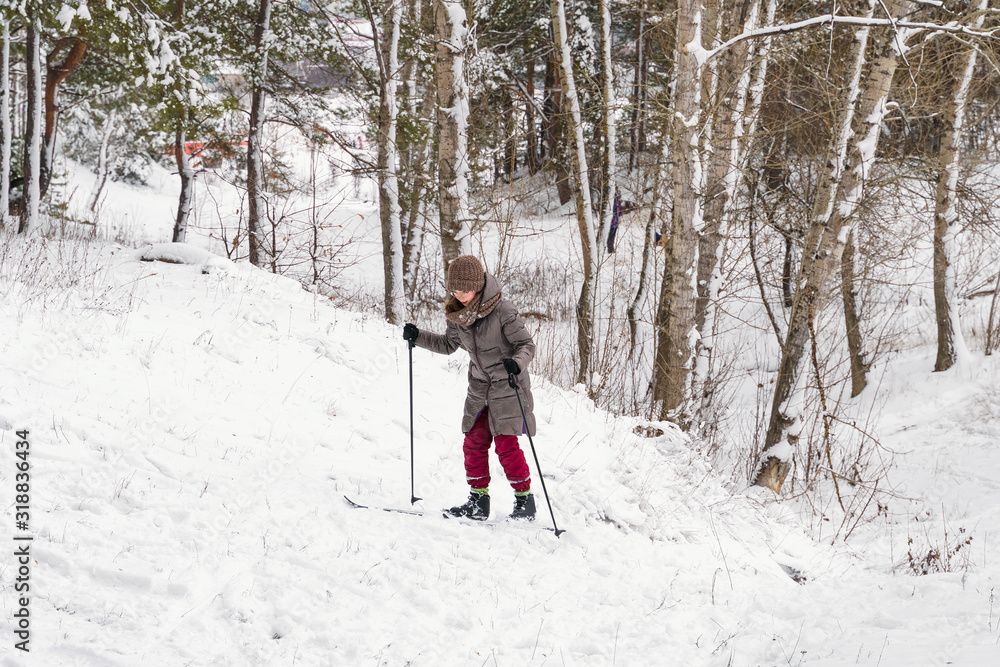 ski girl climbing uphill in winter forest