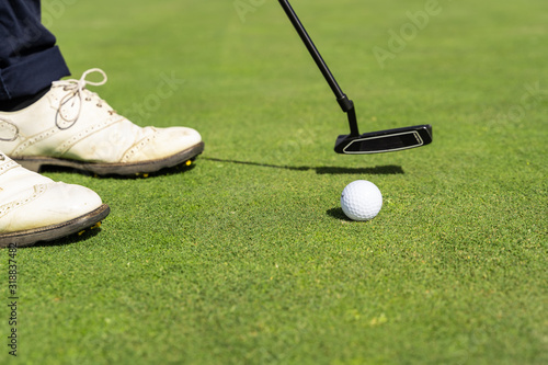 Golf ball and a person's shoes on a golf course
