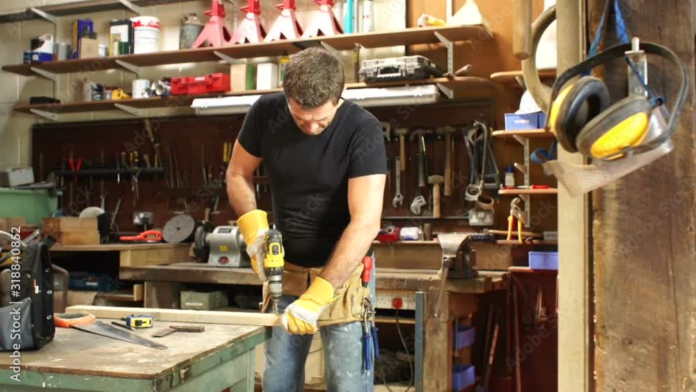 Carpenter / Joiner is in his workshop using a cordless Drill. Tracking Shot. Carpenter / Joiner is in his workshop using a cordless Drill. Tracking Shot.