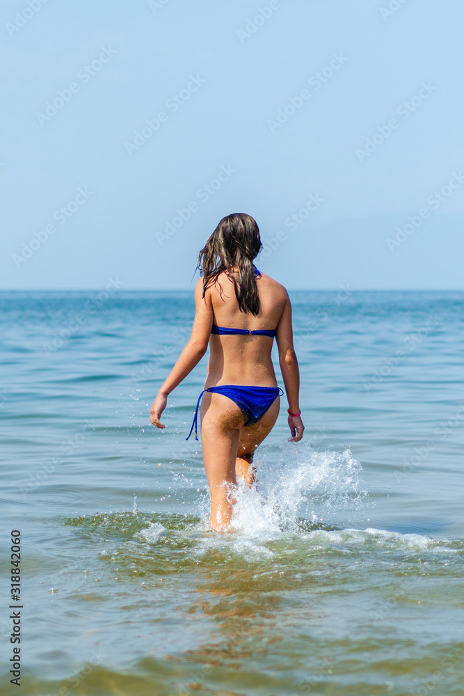girl in a blue bathing suit in the water. View from the back girl in a blue bathing suit in the water. View from the back