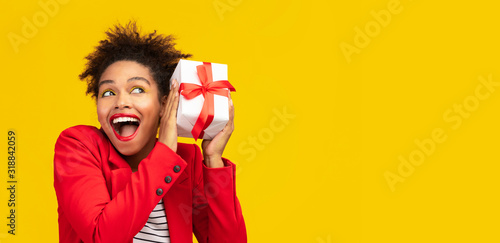 Happy black girl shaking gift box at studio