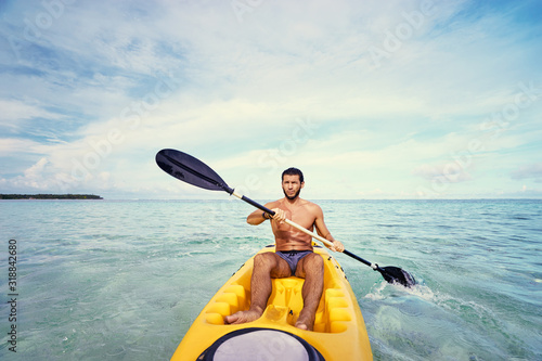 Young man paddling in the sea near the islands. Adventure by kayak.