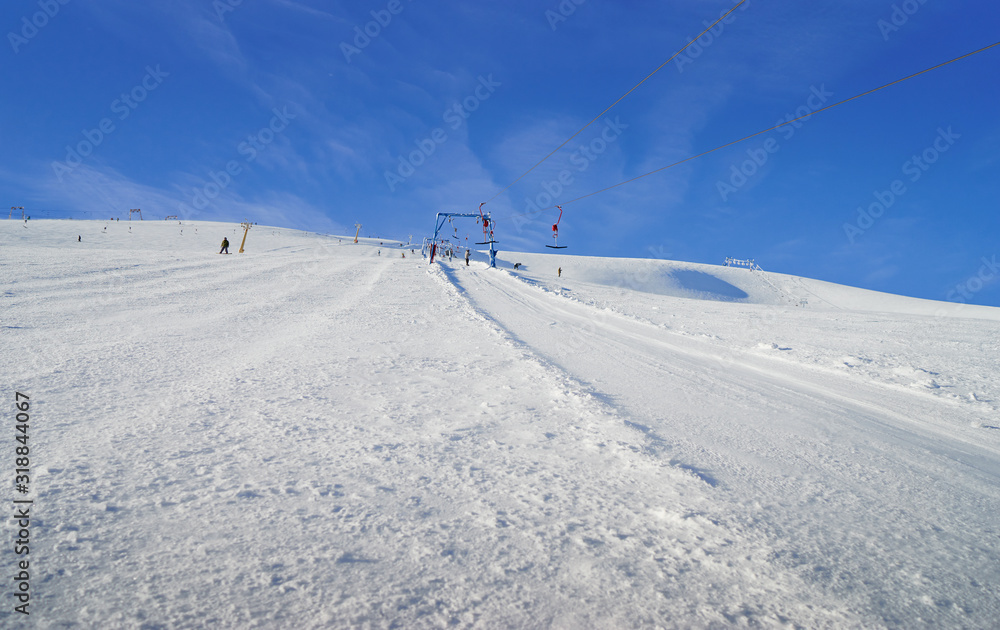 Ski lift going over the snowy mountain and paths from skies and snowboards.
