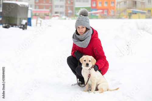 Happy young woman walking with her puppy in winter city © Olya