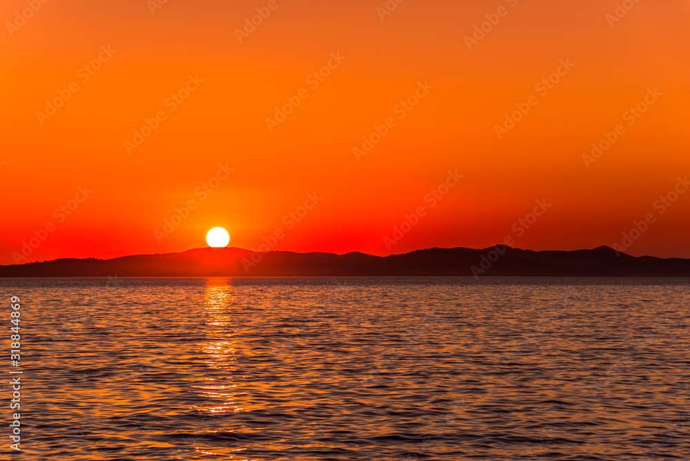 Beautiful orange sky with sunset over sea and mountains horizon, Zadar, Dalmatia, Croatia