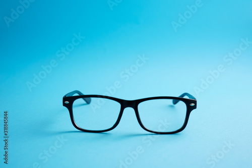 Modern fashionable acetate spectacles, black color, laying on classic blue background. trendy concept