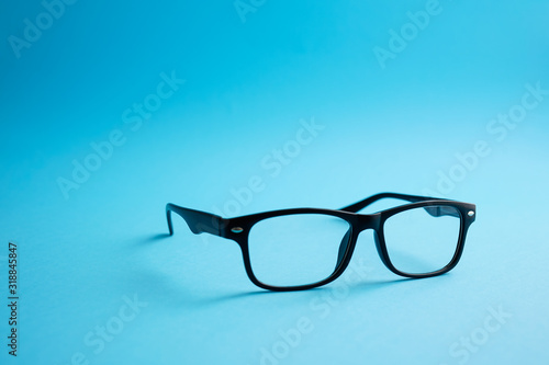 Modern fashionable acetate spectacles, black color, laying on classic blue background. trendy concept