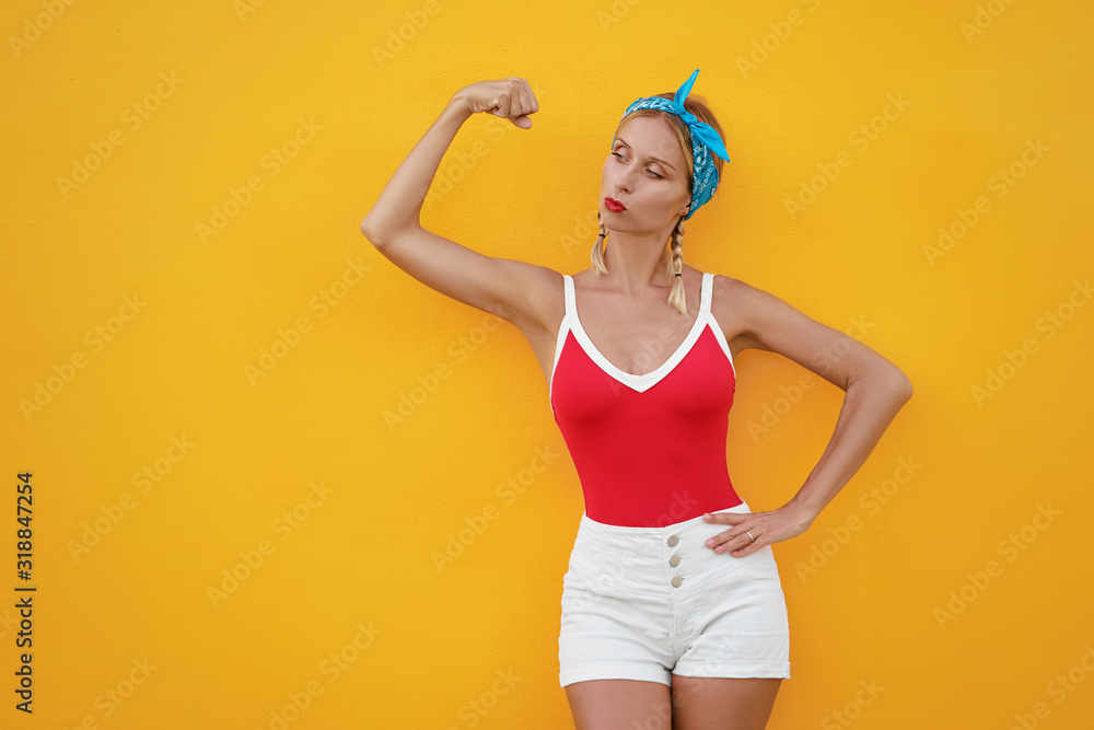 Strong and energy. Pretty young woman showing bicep on her arm. Colorful portrait with yellow background. Strong and energy. Pretty young woman showing bicep on her arm. Colorful portrait with yellow background.