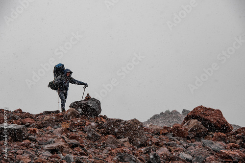 Tourist stands on rocks in snowy weather photo