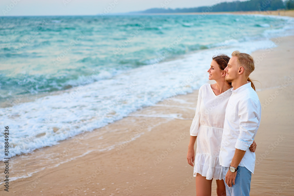Romantic vacation. Love and tenderness. Young loving couple kissing and embracing on the sea sand beach.
