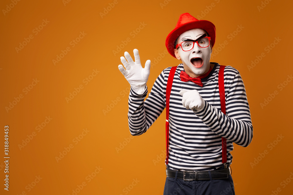 Naklejka premium Happy mime man in red hat, white gloves and striped t-shirt on blank orange background