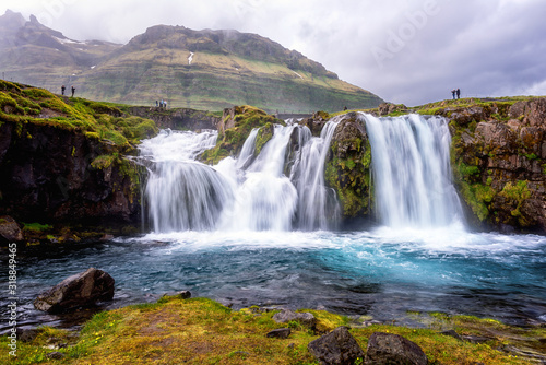 Famous Kirkjufellsfoss waterfall, favorite tourist destination in Iceland. Amazing dramatic landscape, harsh scandinavian nature, outdoor travel background