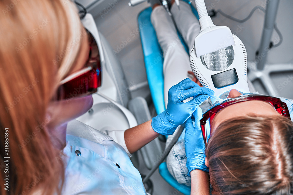 Φωτογραφία Young girl undergoes the procedure of teeth whitening with the help of ultraviol