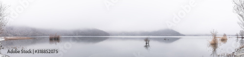 Panoramic view of a mountain lake in the foggy weather
