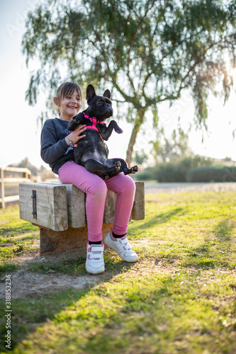 happy girl holding french bulldog in her arms, in the open air park