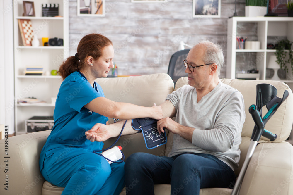 Young doctor in nursing home taking digital blood pressure