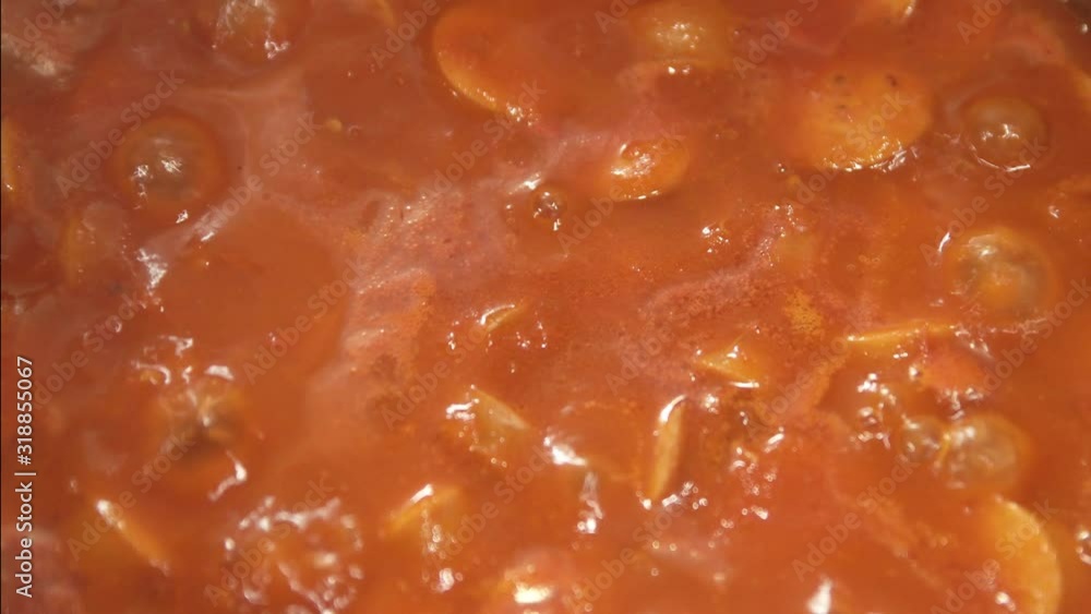 Boiling sausage in a red tomato sauce. Close up and depth of field. Perfect for text and copy space or background. Boiling sausage in a red tomato sauce. Close up and depth of field. Perfect for text and copy space or background.