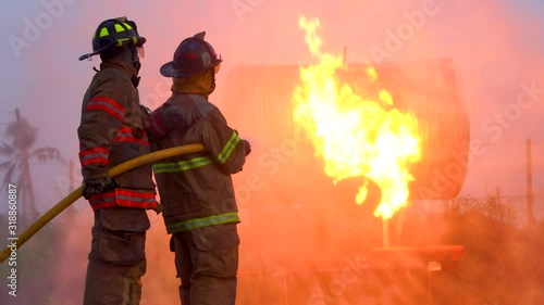 Two firefighters in the fire scene Both of them are performing their duties in full capacity.