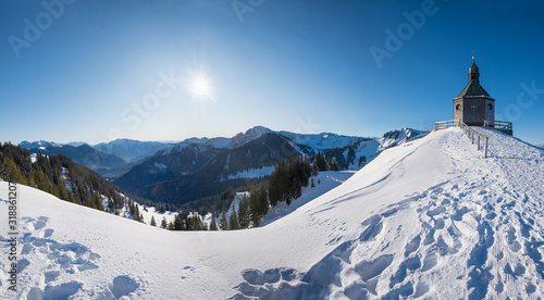 beautiful chapel in winter landscape, popular tourist destination with view to bavarian alps