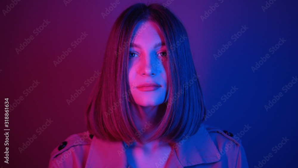 Seductive young woman with straight hair looking at camera, dancing. Magical power of femininity.Charismatic. Neon lighting. Shooting, footage. Style, fashion