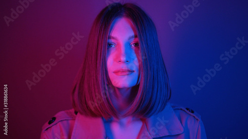 Seductive young woman with straight hair looking at camera, dancing. Magical power of femininity.Charismatic. Neon lighting. Shooting, footage. Style, fashion