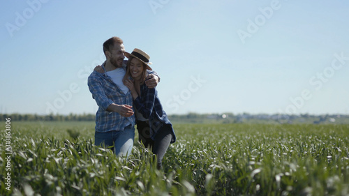 Happy young couple wearing plaid shirts. Man and woman walking through field, hugging. Outdoors. Relationship. Idea. Concept. Summertime, fine, model, female, awesome, breathtaking, amazing, stunning