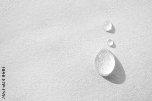 Water drop on white paper textured background with copy space and selective focus, close-up. Concept moisturizing macro, top view