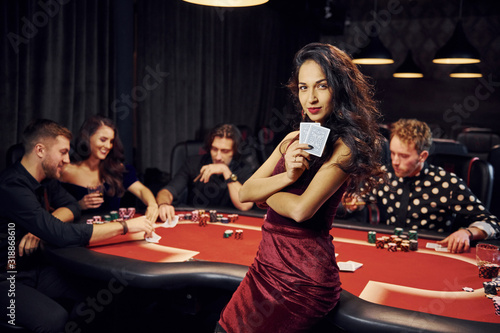 Portrait of beautiful woman. Group of elegant young people that playing poker in casino together