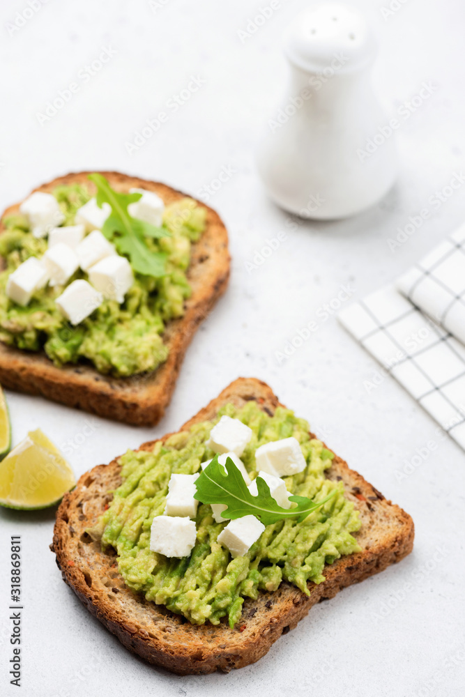 Avocado and feta cheese whole grain toast. Healthy vegetarian snack food or breakfast on white background Avocado and feta cheese whole grain toast. Healthy vegetarian snack food or breakfast on white background