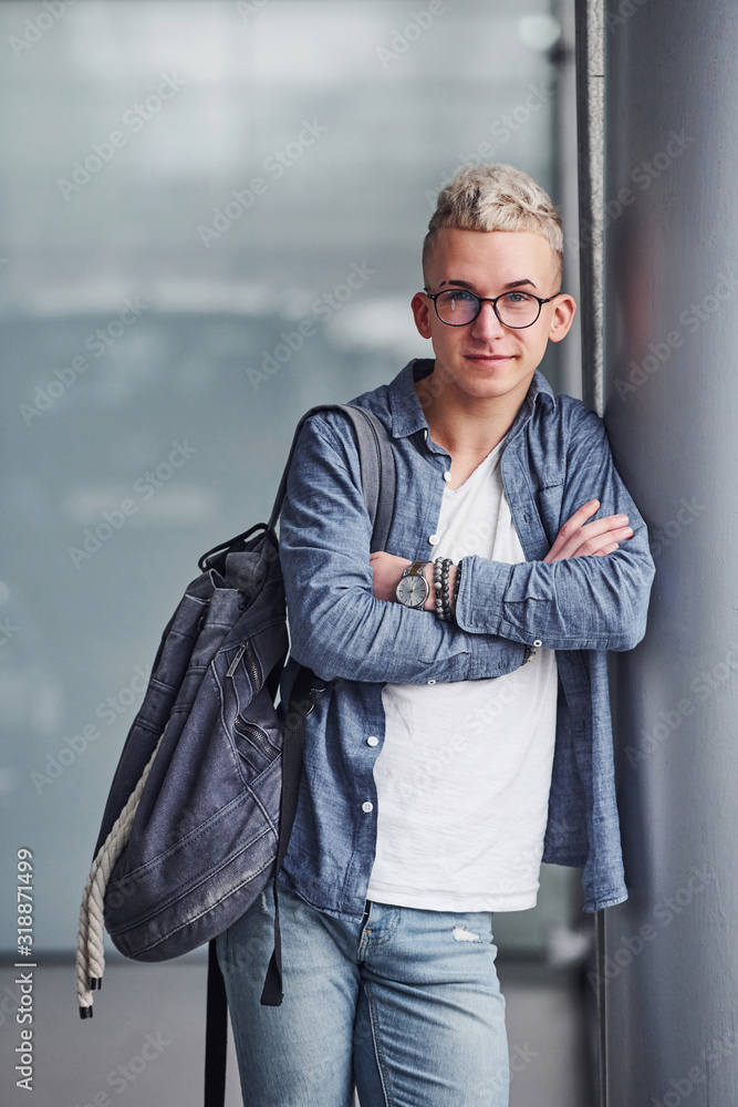 Obraz premium Young hipster guy in nice clothes stands indoors against grey background