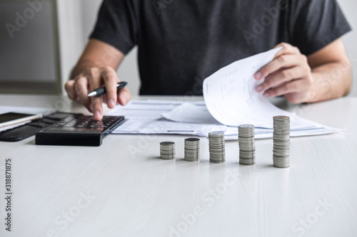 Images of stacking coin pile and Husband using calculator to calculating expenditure receipt bills of various activity cost and expenses in home office and written make report to plan of spent