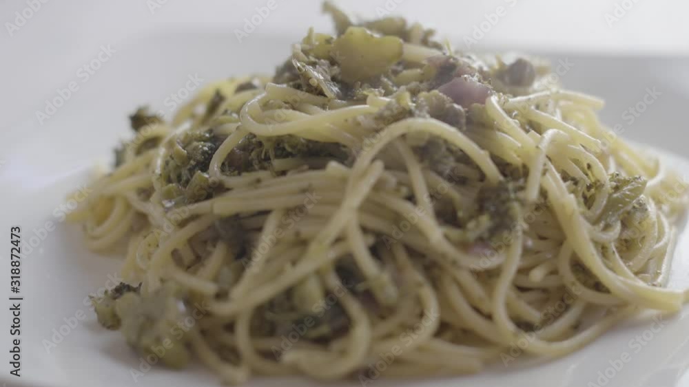 Close-up of a steaming plate of vegan spaghetti with broccoli and capers and a drizzle of extra virgin olive oil poured over it - 4k slog3 ungraded food footage Close-up of a steaming plate of vegan spaghetti with broccoli and capers and a drizzle of extra virgin olive oil poured over it - 4k slog3 ungraded food footage