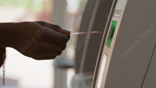 Close-up of man s hand inserting a credti card to withdraw money from bank account. Young african man using an ATM cash machine in a break.