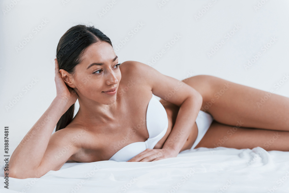Young woman in underwear and with nice body shape lying down in the studio against white background Young woman in underwear and with nice body shape lying down in the studio against white background