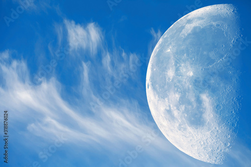 Blue sky with beautiful clouds. The moon with a large increase against the background of clouds and blue sky.