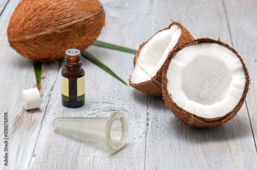 Coconut halved, essential oil in a glass bottle and a vacuum can for facial massage on a gray wooden table. Personal care. Spa treatments. Cosmetology. Natural and organic cosmetics.