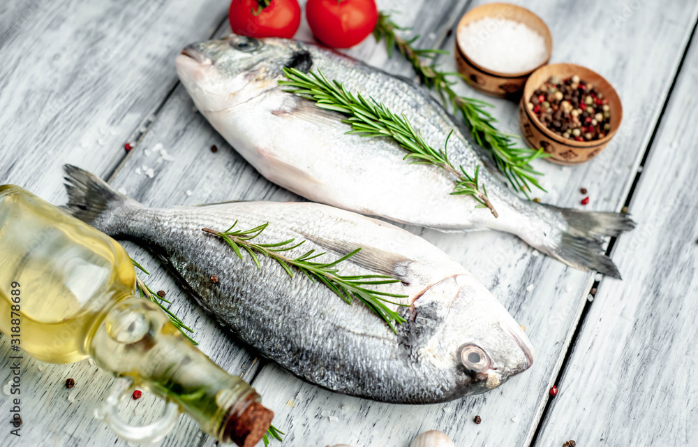 Fresh dorado fish with spices and ingredients for cooking on a wooden table background Fresh dorado fish with spices and ingredients for cooking on a wooden table background