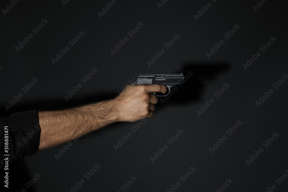 Professional killer with gun on black background, closeup Professional killer with gun on black background, closeup