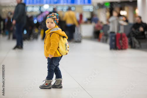 Blonde toddler boy with family, traveling with airplane, running at the airport