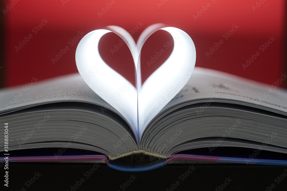 A heart from book pages shines in on a brown background. A heart from book pages shines in on a brown background.