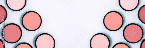 Pink blush and compact powder on a pastel blue background. Banner. Place for text, design. Top view. Trending colors. Makeup. Cosmetic products. Tonal foundation. Flat lay, Layout. Beauty concept. 