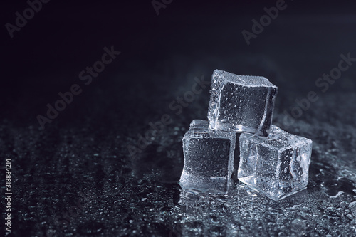 Fototapeta Naklejka Na Ścianę i Meble -  Crystal clear ice cubes with water drops on black background. Space for text