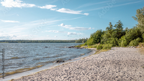 Fototapeta Naklejka Na Ścianę i Meble -  Edge of the water lake with sand and stones and trees on the background
