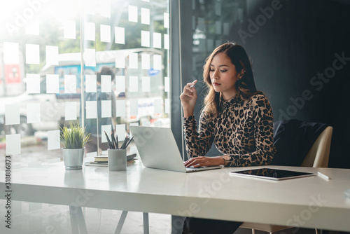 Young asian businesswoman sitting on her workplace in the office. Young woman working at laptop in the office.