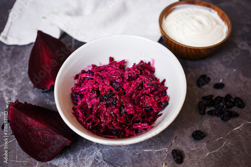 A light simple salad of beets and raisins with sour cream on a dark gray marble background. Around - the ingredients. The concept of simple homemade food  healthy eating.